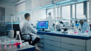 Medical Science Laboratory with Diverse Multi-Ethnic Team of Biotechnology Scientists Developing Drugs, Microbiologist Working on Computer with Display Showing Gene Editing Interface. stock photo