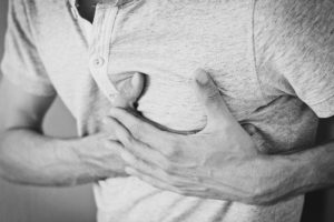 an adult male clutches the left side of his chest in pain - heart attack