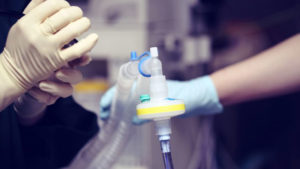 Close up of a healthcare professional wearing latex gloves holding a ventilator device